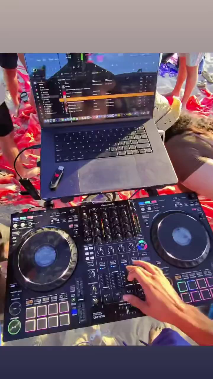 DJ Maduro performing from a controller and laptop at a beach event
